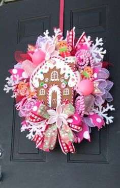 a wreath with a gingerbread house and candy canes hanging from the front door