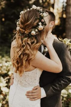 a bride and groom embracing each other in front of some trees with flowers on their head