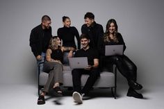 a group of people sitting on top of a couch with laptops in their hands