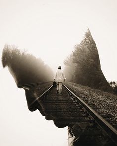 a man walking down train tracks with his reflection in the side of him's face