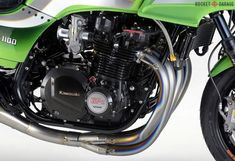 a green motorcycle parked on top of a white floor next to a black and silver hose