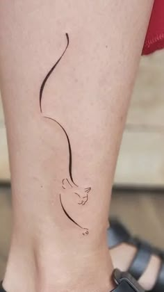 a woman's foot with a small cat tattoo on the left side of her leg