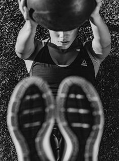 black and white photograph of a man holding a ball above his head in the grass