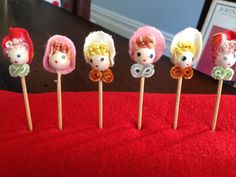 five little lollipops are lined up on a red tablecloth with the same design