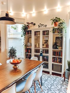 a dining room table and chairs with bookshelves in the background