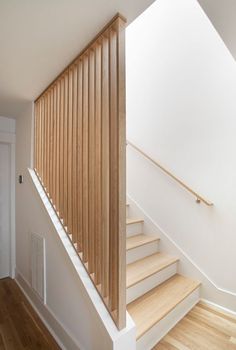 a wooden stair case next to a white wall