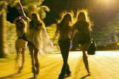 three women are walking down the street at night with their hair blowing in the wind