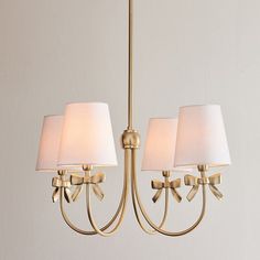 a chandelier with three lamps hanging from it's sides and two white shades