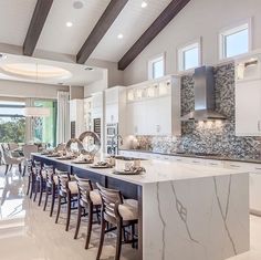 a large kitchen with white cabinets and marble counter tops, along with an island in the middle