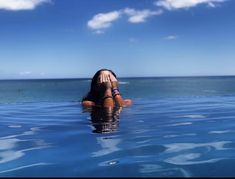 a woman is floating in the ocean with her hands on her face and looking at the camera