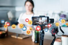 a woman is recording the video on her cell phone with emoticions surrounding her