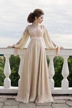 a woman in a long dress standing on a balcony