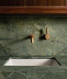 a bathroom sink with two faucets on it's side and marble counter top