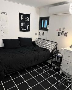 a black and white bedroom with a bed, desk, dresser and pictures on the wall