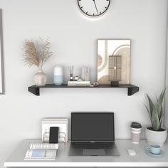 a laptop computer sitting on top of a desk next to a clock and other items