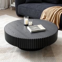 a coffee table with a cell phone and candle on it in front of a couch