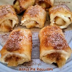 apple pie roll - ups on a plate with powdered sugar