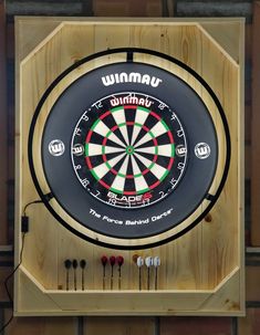 a dart board mounted to the side of a wall with darts on it and an arrow in the center