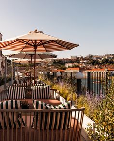 two lounge chairs and an umbrella are on the roof top terrace with city views in the background