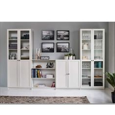 a living room filled with white furniture and pictures on the wall above it's bookshelves