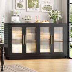 a black cabinet with glass doors and pictures on the wall above it in a living room