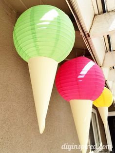 two ice cream cones hanging from the side of a building with paper lanterns attached to it