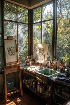 an artist's studio with large windows and lots of art supplies on the table