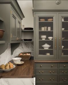 a kitchen with gray cabinets and marble counter tops