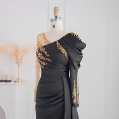 a dress on a mannequin with gold sequins and an open shoulder