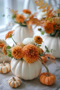 some white pumpkins and flowers on a table