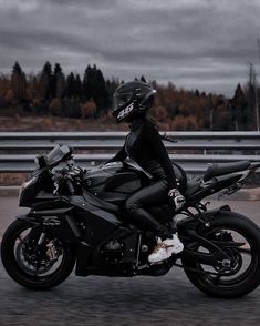 black and white photograph of a person riding a motorcycle on the road with trees in the background