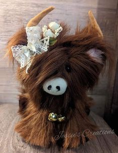 a stuffed animal with horns and lace on it's head sitting on a wooden surface