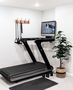 a home gym with treads, monitor and exercise mat in front of the tv