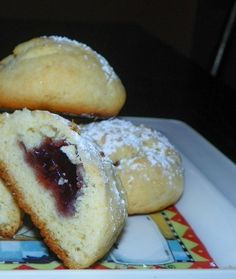 several pastries on a colorful plate with powdered sugar and jelly filling them up