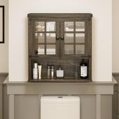 a bathroom with a wooden cabinet above the toilet and other items on the shelf next to it