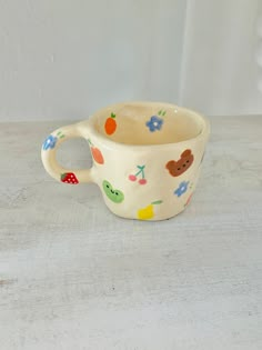 a ceramic cup with colorful designs on it sitting on a white counter top next to a wall