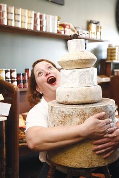 a woman is holding a large stack of cheese