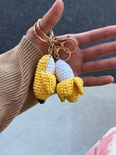 a hand holding two crocheted yellow and white baby booties on it's fingers