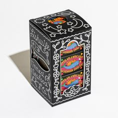 a black box with designs on it sitting on a white surface next to a shadow