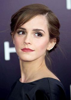 a woman with brown hair wearing a black dress and diamond earrings on her left ear