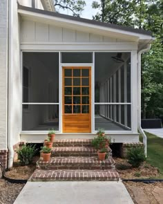 a small white house with an orange door and windows on the front porch, surrounded by brick steps