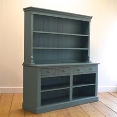 a blue bookcase sitting on top of a wooden floor next to a white wall