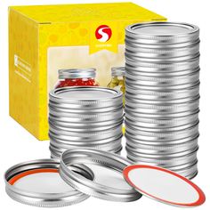 a stack of silver tins with red and white lids next to a yellow box