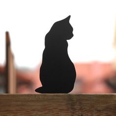 a black cat sitting on top of a wooden table next to a window sill