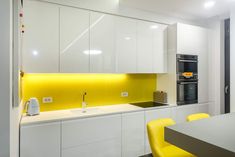 a modern kitchen with yellow accents and white cabinetry, along with bright yellow chairs