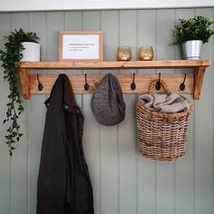 a coat rack with two coats hanging from it's hooks and some plants on the wall