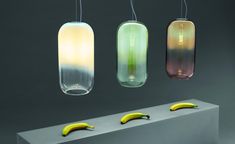 three hanging glass vases with bananas in front of them and one banana on the bottom