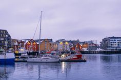 several boats are docked in the water next to some buildings and other large buildings at dusk