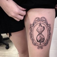 a woman's thigh with an hourglass tattoo on it