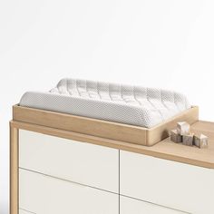 a baby crib sitting on top of a dresser next to a white wall and drawers